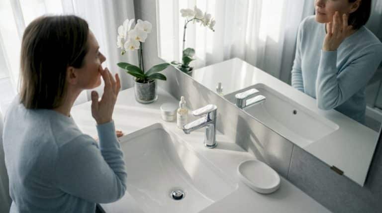 Woman applies serum in softly lit bathroom